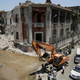 Workers clear rubble at the site of an explosion near the Italian Consulate in downtown, Cairo, Egypt.